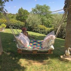 a hammock is set up in the grass with pillows and blankets on it