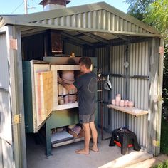 a man standing in front of a storage shed with pots and pans on it