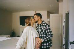 a man and woman kissing in front of a bed