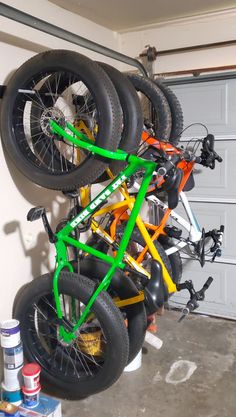 several bikes are stacked on top of each other in a garage with paint cans next to them