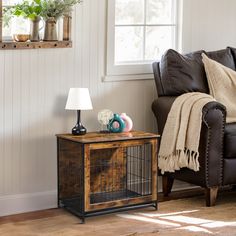 a living room with a couch, chair and small dog cage on the end table