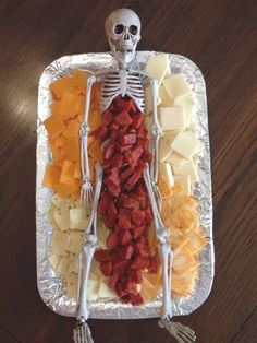 a skeleton made out of cheese and meats on a tray with other food items