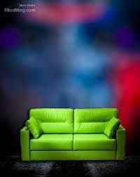 a green couch sitting on top of a black floor next to a red and blue wall