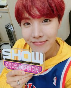 a young man with red hair is holding up a small box that says show champion