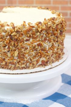 a cake with white frosting and nuts on top sitting on a blue and white checkered tablecloth