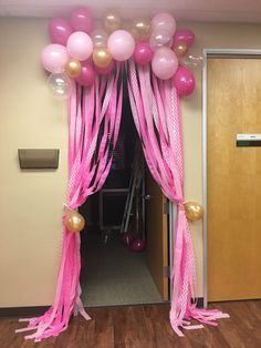 balloons and streamers decorate the entrance to a room decorated for a baby's first birthday