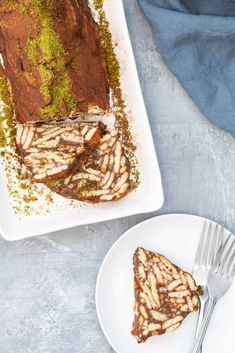 a piece of chocolate cake on a plate with a fork next to it and another slice in the background