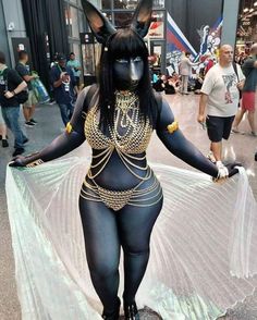 a woman dressed in black and gold poses for the camera with her dog costume on