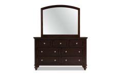 the dresser has a mirror on it and is dark brown with white trimmings