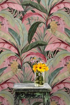 a vase filled with yellow flowers sitting on top of a table next to a wall