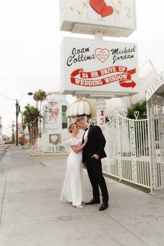 a bride and groom kissing in front of the sign for their wedding venue, las vegas