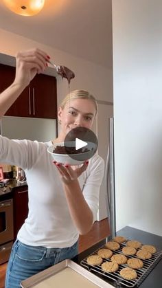 a woman is cooking cookies in the kitchen and she is holding a spatula over her face