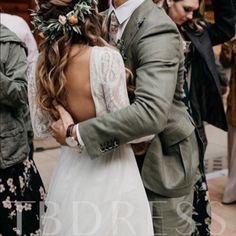 a man in a suit and tie hugging a woman wearing a flower crown on her head