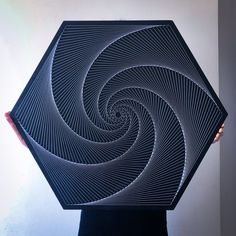 a person holding up a black and white art piece that looks like a spiral design