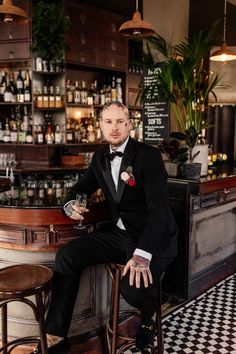 a man in a tuxedo sitting at a bar