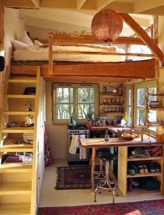 a loft with stairs leading up to the kitchen and living room area, as well as storage space