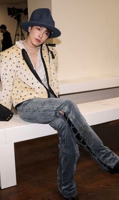 a person sitting on a bench wearing a hat and jacket with polka dot print shirt