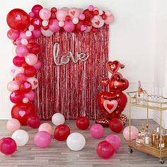 balloons and streamers are on the floor next to a red curtain with love written on it