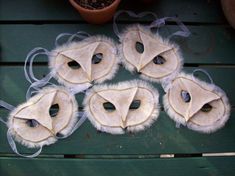 six animal masks sitting on top of a green bench next to a potted plant