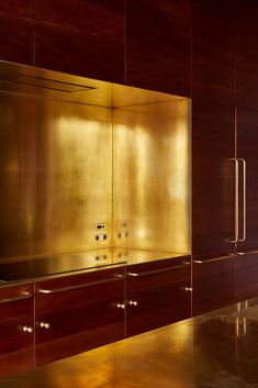 a kitchen with shiny gold cabinets and stainless steel counter tops