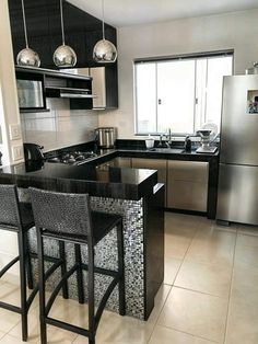 a modern kitchen with stainless steel appliances and black counter tops, along with two bar stools