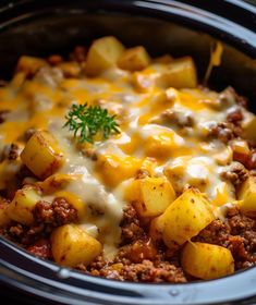 a crock pot filled with ground beef and potatoes covered in cheese, gravy