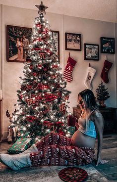 a woman sitting in front of a christmas tree