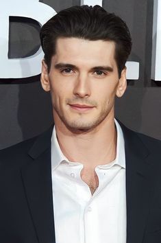 a man in a black suit and white shirt posing for the camera at an event