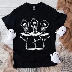 Dancing Skeletons, Skeleton Shirt, Ballet Shirt, Halloween Shirt, Spooky Season, Spooky Shirt, Trendy Halloween Dark Clowncore, Dark Memecore, Skinny Shirt, Dancer Shirt, Theatre Shirt, Retro Graphic Tee This Soft-style t-shirt puts a new spin on casual comfort. Made from very soft materials, this tee is 100% cotton for solid colors. Heather colors and sports grey include polyester. The shoulders have twill tape for improved durability. There are no side seams. The collar is made with ribbed kni Fitted Funny Black T-shirt, Punk Tops For Costume Party In Fall, Punk Tops For Fall Costume Party, Punk Style Fall Tops For Costume Party, Fitted Black T-shirt For Halloween, Black Novelty Shirt With Graphic Print, Halloween Punk Top With Skull Print, Punk Style Short Sleeve Halloween Tops, Novelty Black T-shirt With Character Print