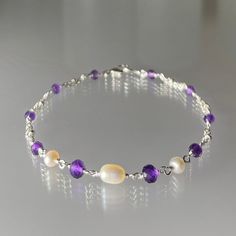 Genuine, premium-quality, faceted purple amethyst and freshwater pearl bracelet, hand-made in sterling silver. This beautiful and feminine bracelet features genuine, African purple amethyst gemstones and creamy-white freshwater pearls. The pearls are centred, with the faceted, sparkling amethyst stones securely and impeccably wire-wrapped, on both sides, to segments of double-strand sterling silver chain.  This bracelet is finished with a sturdy sterling silver lobster-claw clasp.  An elegant and fashionable bracelet perfect by itself or stacked with others. This bracelet is enlarged to show details. Amethyst is the birthstone for February and pearl for June. Details: *  bracelet length: choose at check-out (see notes below re measurement) genuine faceted peridot:  4.5, 3.75 and 3.5 mm fre Freshwater Pearl Bracelet, Silver Chain Bracelet, Amethyst Stone, June Birth Stone, Amethyst Gemstone, Purple Amethyst, Pearl Bracelet, Fashion Bracelets, Beautiful Bracelet