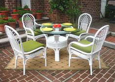 a white table with four chairs around it on a rug in front of a brick wall