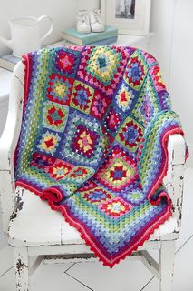 a white chair with a colorful crocheted blanket on it