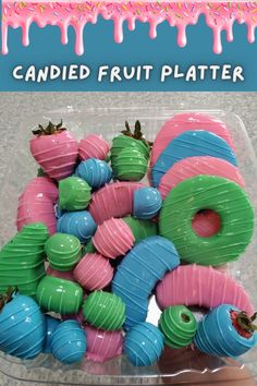 a plastic container filled with candy covered in frosting and sprinkles next to a sign that says candied fruit platter