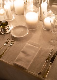 the table is set with silverware, candles and napkins for dinner guests to enjoy