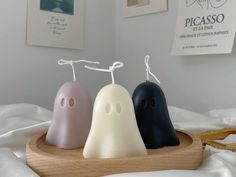 three ghost candles sitting on top of a wooden tray