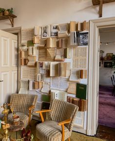 two chairs and a table in front of a wall with many books on the shelves