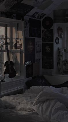 a bedroom with a guitar hanging from the ceiling next to a window and bed in front of it