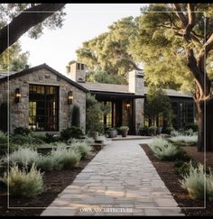 a stone house surrounded by trees and plants in front of the entrance to the building