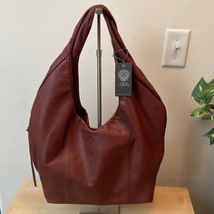 Extremely Soft, Supple Leather Slouchy Handbag! Color: Bordeaux Bite Leather Twisted Handle; Magnetic Snap Closure At Center Top Exterior: Zip Pocket At Gussetwith Tassel Zip Pull Interior: Lined In Microsuede/Pu; Zip Pocket, 2 Media Pockets And Gray Leather Slip Pocket With Logo Slot Light Steel Grey Lining Approx: 10" W X 19" H X 4.5" D ; Handle Drop: 11" Made In India No Dust Bag Carry It In Hand Or On Your Shoulder! This Is A Very Nice Bag Elegant Leather-lined Hobo Bag For On-the-go, Elegant Hobo Bag For On-the-go, Leather Hobo Bag With Removable Pouch For Shopping, Cognac Textured Leather Hobo Shoulder Bag, Textured Leather Bucket Bag For Errands, Cognac Leather Shoulder Bag With Handle Drop, Everyday Textured Leather Cognac Hobo Bag, Cognac Textured Leather Hobo Bag For Everyday, Everyday Cognac Textured Leather Hobo Bag