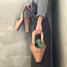 a woman holding two paper bags with plants in them