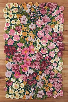 a rug with flowers on it sitting on top of a wooden floor in front of a wall