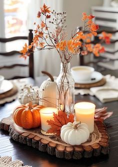 a table topped with candles and pumpkins on top of a wooden tray covered in leaves