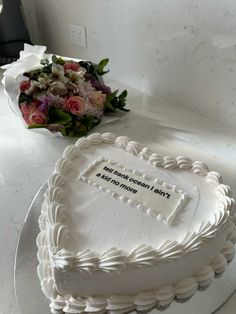 a heart shaped cake sitting on top of a table next to a bouquet of flowers