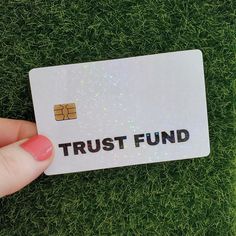 someone holding up a trust fund card in their hand on the grass with glitters