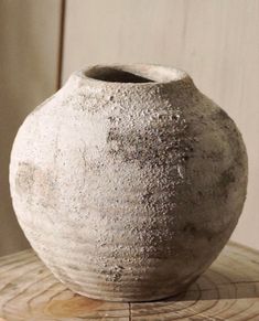 a white vase sitting on top of a wooden table