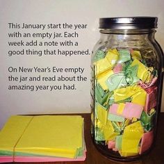 a jar filled with lots of colorful paper on top of a wooden table next to a notepad