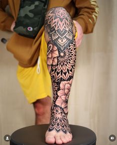 a person standing on top of a stool with a tattoo on their arm and leg