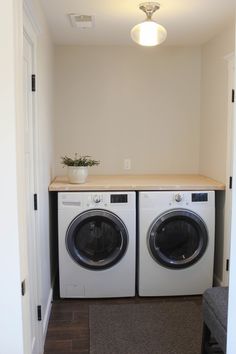 a washer and dryer in a small room next to a door with a plant on top