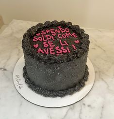 a black cake with pink writing on it sitting on top of a marble countertop