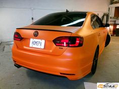 an orange car parked in a garage with the license plate on it's back